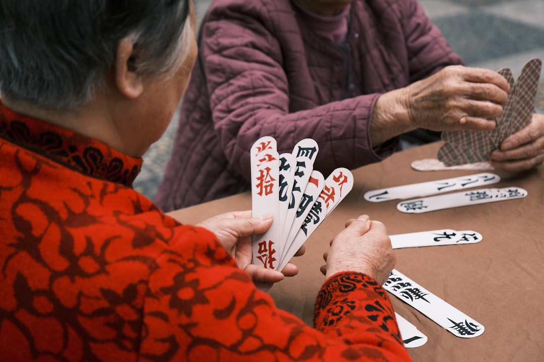 woman in red and black long sleeve shirt holding playing cards