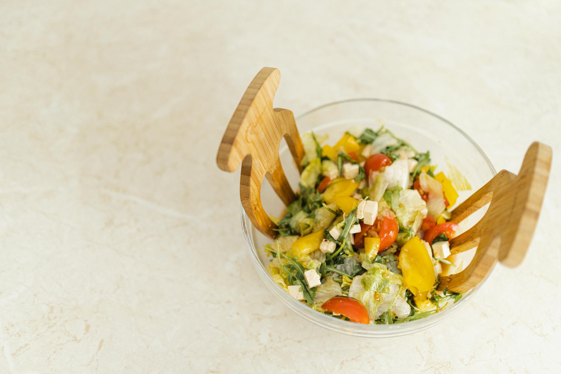 Refreshing vegetable salad with cherry tomatoes, bell peppers, and feta cheese in a clear glass bowl.