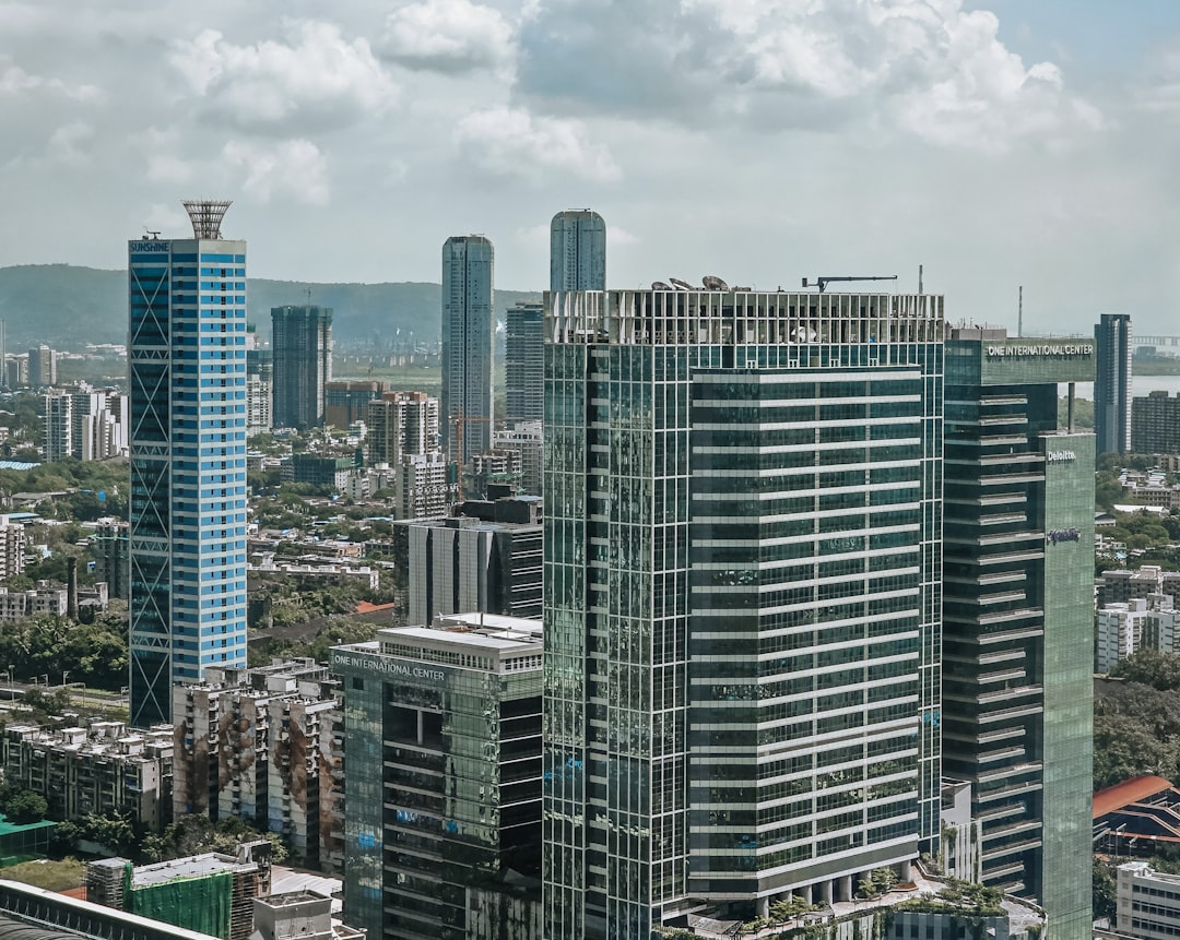 Modern skyscrapers rise above a bustling cityscape under clouds.
